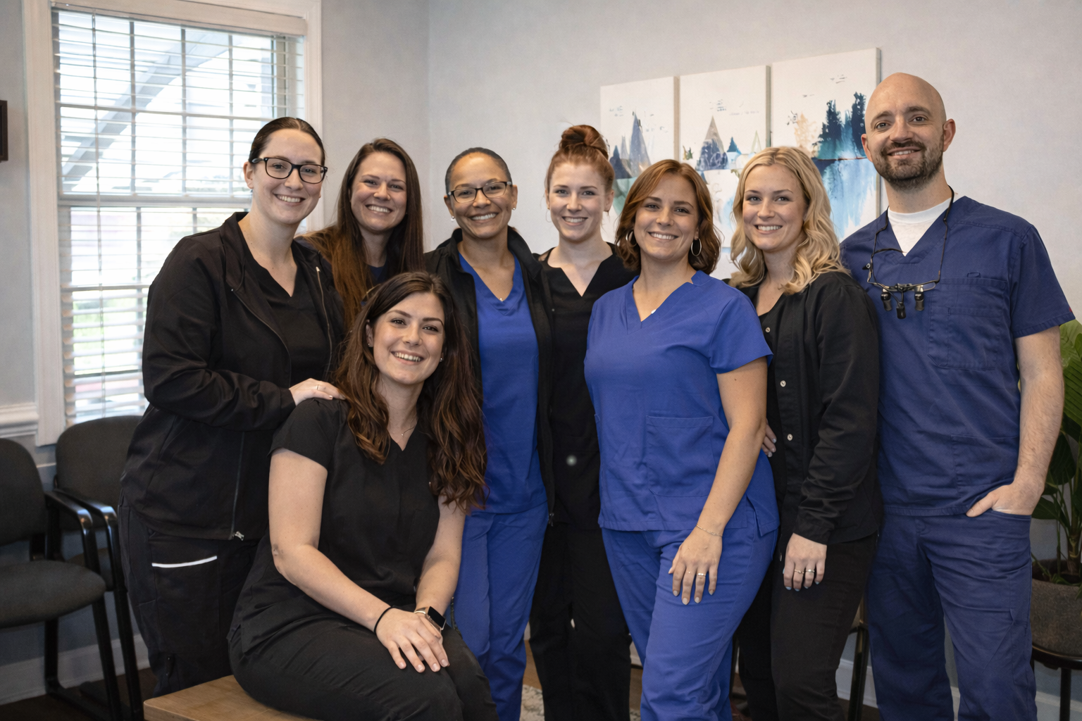 Apple Blossom Dentistry team together inside their Winchester, VA clinic reception area, including the dentist on the right, creating a welcoming and professional atmosphere.